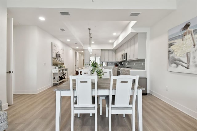 dining space featuring visible vents, baseboards, and light wood finished floors