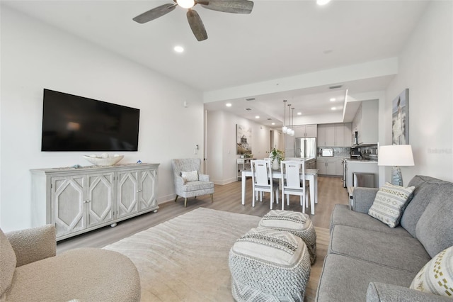 living room featuring recessed lighting, baseboards, light wood finished floors, and ceiling fan