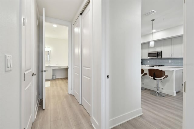 hall featuring light wood finished floors and visible vents