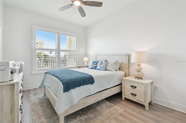 bedroom with baseboards, light wood-style floors, and a ceiling fan