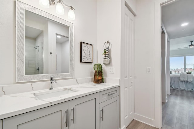 ensuite bathroom featuring a stall shower, wood finished floors, connected bathroom, ceiling fan, and vanity