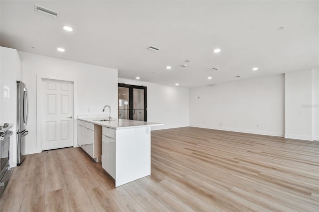 kitchen with visible vents, light wood-type flooring, freestanding refrigerator, and a sink