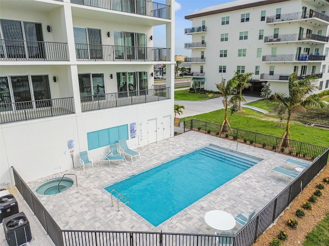 pool featuring a patio, fence, and a hot tub