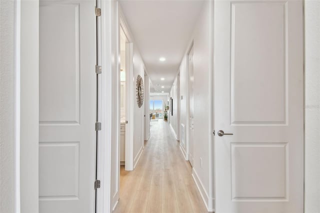 corridor featuring recessed lighting, baseboards, and light wood finished floors