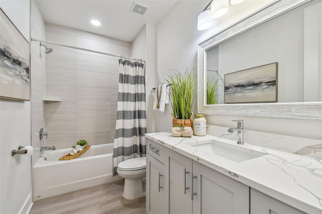 bathroom with vanity, wood finished floors, visible vents, toilet, and shower / tub combo with curtain