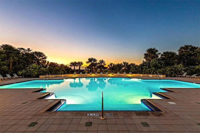 pool at dusk with a patio area