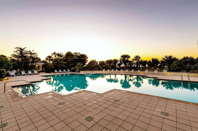 pool at dusk with a patio area