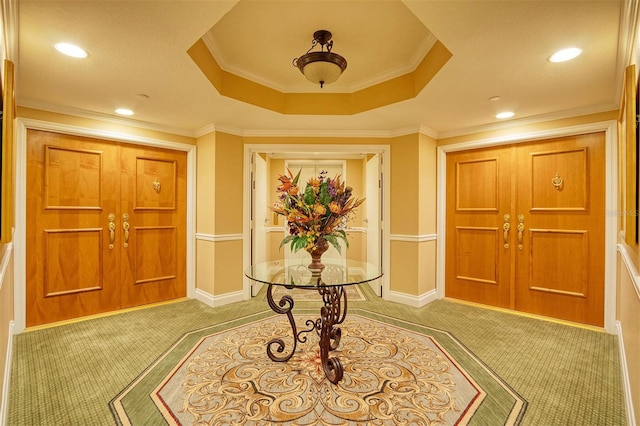 carpeted foyer entrance featuring crown molding and a tray ceiling