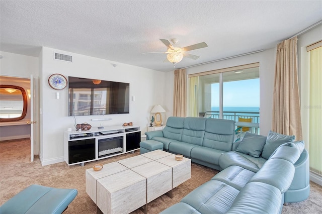 living room with light carpet, ceiling fan, a textured ceiling, and a water view