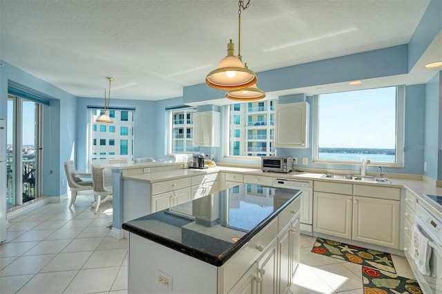 kitchen with decorative light fixtures, a healthy amount of sunlight, a center island, and white cabinetry