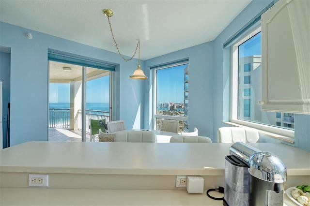 kitchen with hanging light fixtures, white cabinetry, and a water view