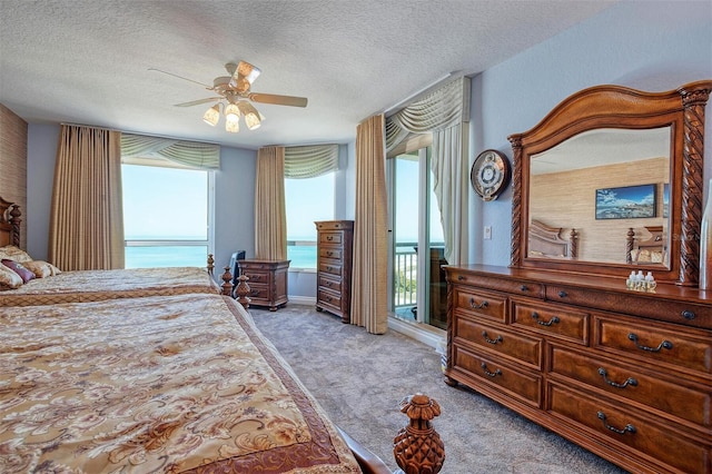 bedroom with light carpet, access to exterior, a water view, ceiling fan, and a textured ceiling