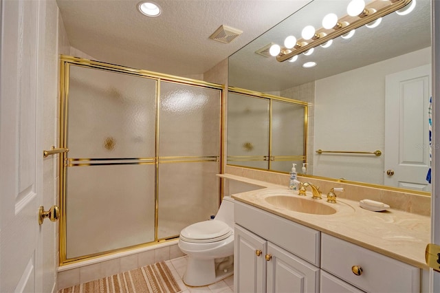 bathroom featuring large vanity, a textured ceiling, toilet, a shower with shower door, and tile floors