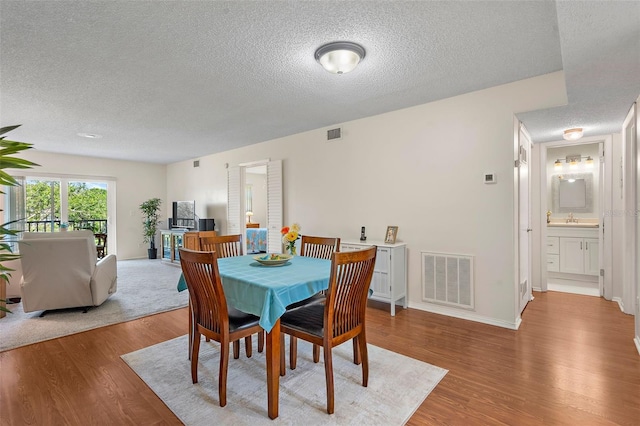 dining area featuring sink, a textured ceiling, and light wood-type flooring