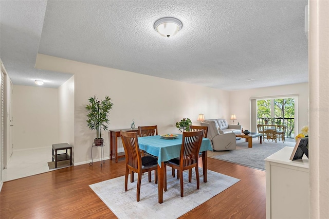 dining room with wood-type flooring and a textured ceiling