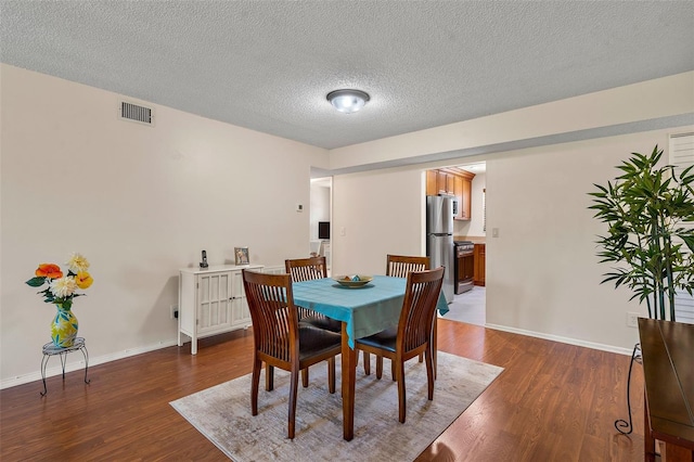 dining area with a textured ceiling and dark wood-type flooring