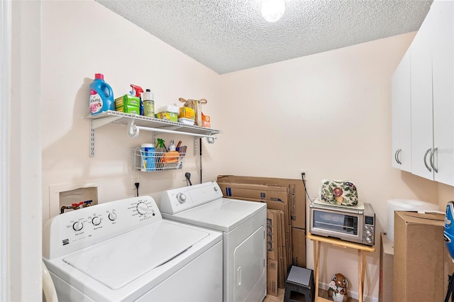 washroom with washing machine and clothes dryer, cabinets, and a textured ceiling