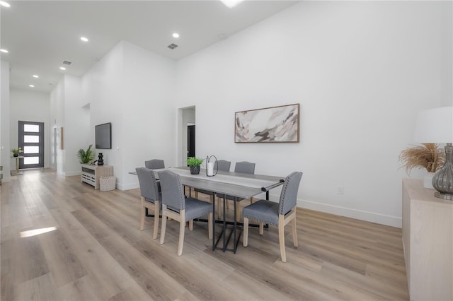 dining room featuring a high ceiling and light hardwood / wood-style flooring