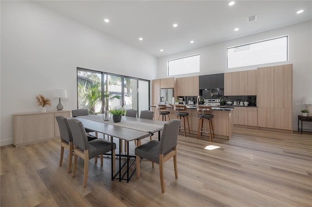 dining space with light hardwood / wood-style flooring and a high ceiling