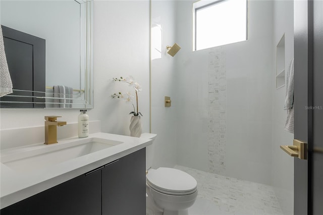 bathroom with toilet, vanity, and tiled shower