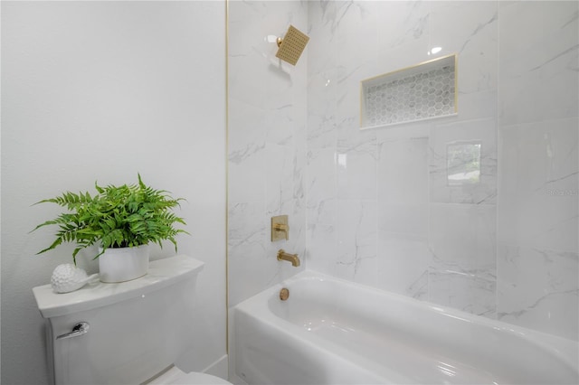 bathroom with toilet and tiled shower / bath