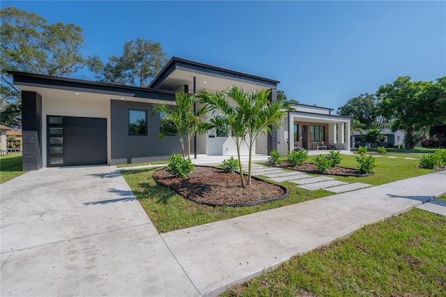 contemporary house featuring covered porch, a front yard, and a garage