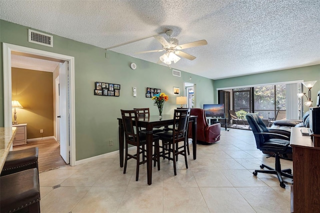 dining room featuring a textured ceiling, ceiling fan, and light tile floors