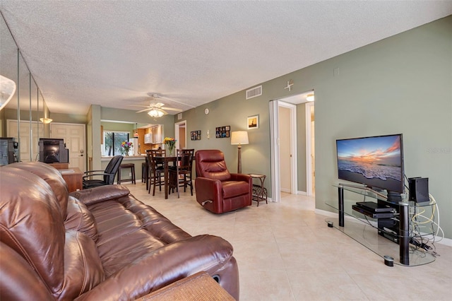 living room featuring tile flooring, ceiling fan, and a textured ceiling