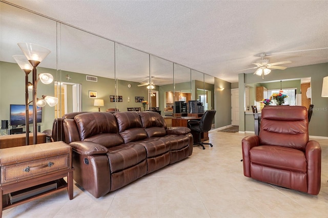 tiled living room with a textured ceiling and ceiling fan