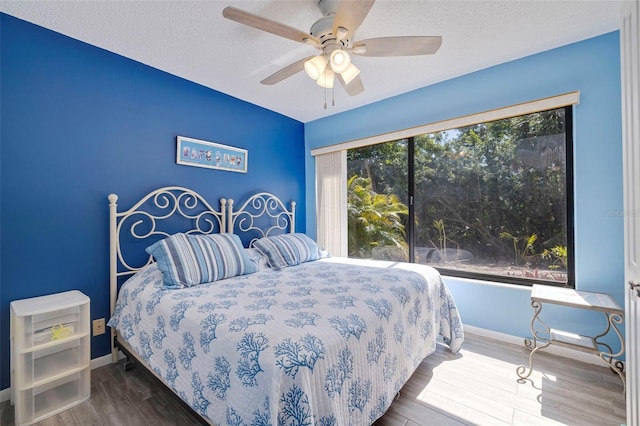 bedroom with dark hardwood / wood-style floors, ceiling fan, and a textured ceiling