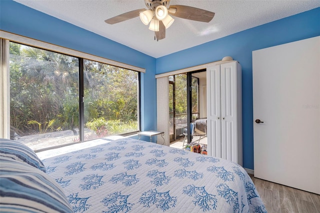 bedroom featuring a textured ceiling, ceiling fan, hardwood / wood-style flooring, and access to exterior