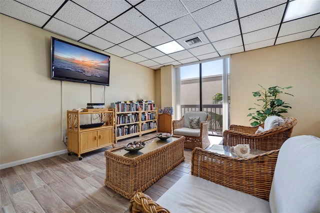 sitting room with a drop ceiling and hardwood / wood-style flooring