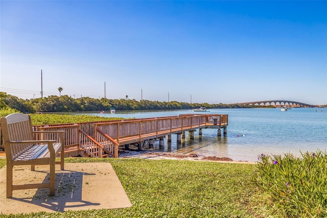 view of dock with a lawn and a water view