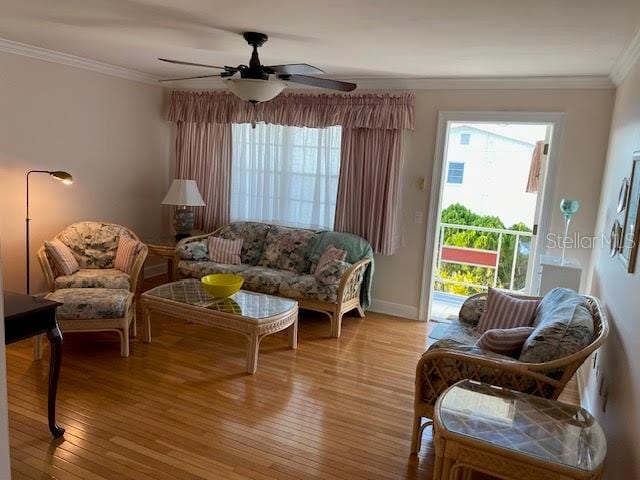 living room with ornamental molding, light hardwood / wood-style flooring, a healthy amount of sunlight, and ceiling fan