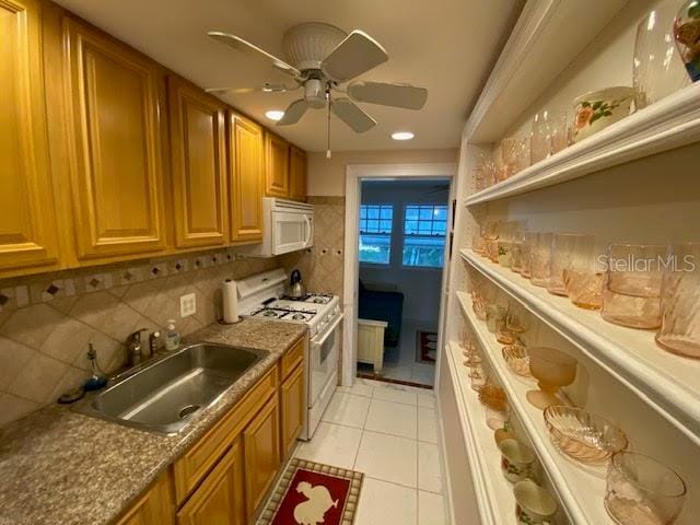 kitchen featuring white appliances, light tile flooring, backsplash, sink, and ceiling fan