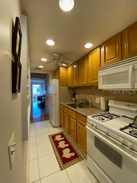 kitchen with white appliances, ceiling fan, light tile floors, and tasteful backsplash