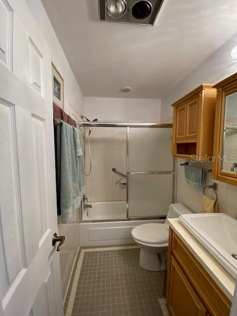 full bathroom featuring toilet, shower / bath combination with glass door, vanity, and tile flooring