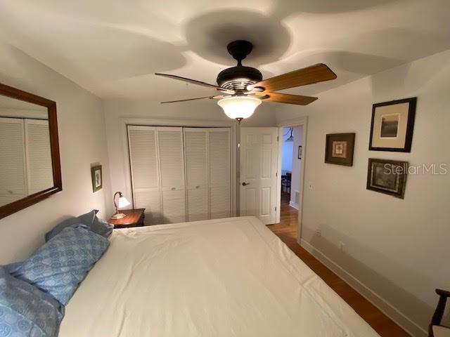 bedroom with a closet, dark wood-type flooring, and ceiling fan