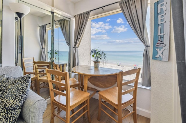 dining space featuring hardwood / wood-style floors, a water view, and a beach view