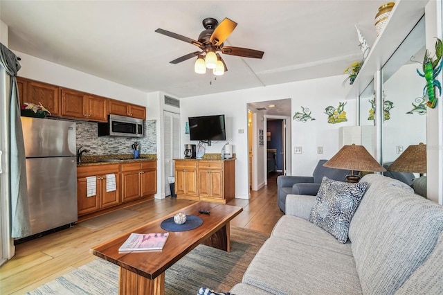 living room featuring ceiling fan and light hardwood / wood-style floors