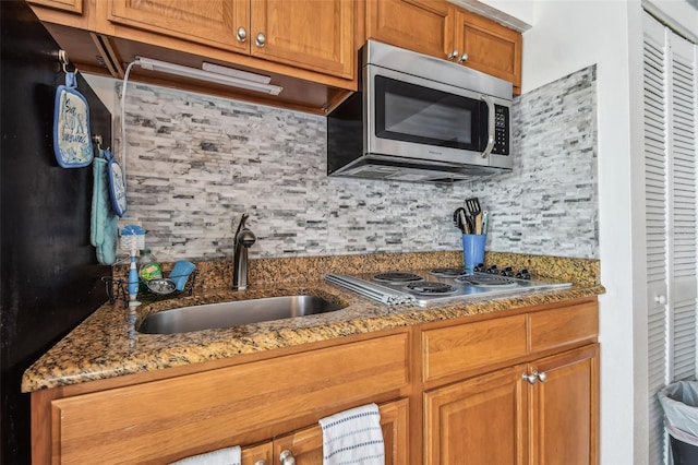 kitchen with tasteful backsplash, sink, stainless steel appliances, and stone countertops