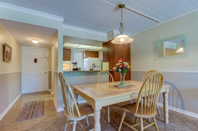 tiled dining area featuring ornamental molding and a textured ceiling