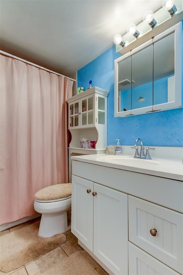 bathroom featuring tile flooring, vanity, and toilet