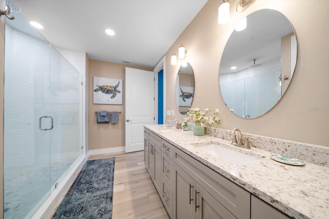 bathroom featuring an enclosed shower, hardwood / wood-style floors, and double sink vanity