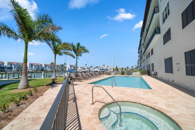 view of pool featuring a patio, a water view, and a community hot tub