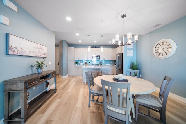 dining room with light hardwood / wood-style floors, sink, and a chandelier