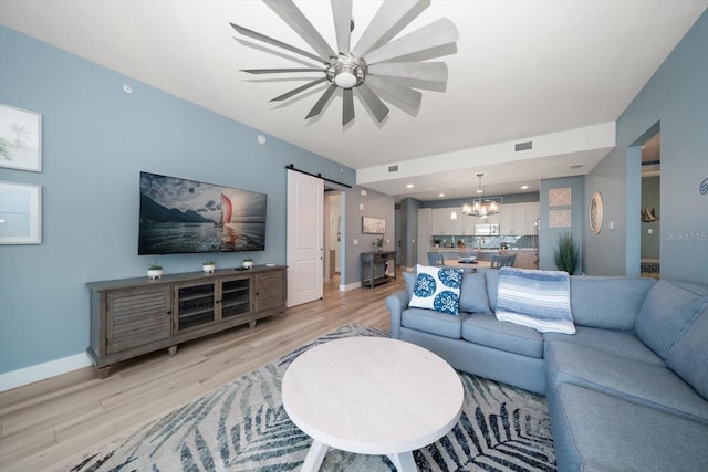 living room with a chandelier, light hardwood / wood-style flooring, and a barn door