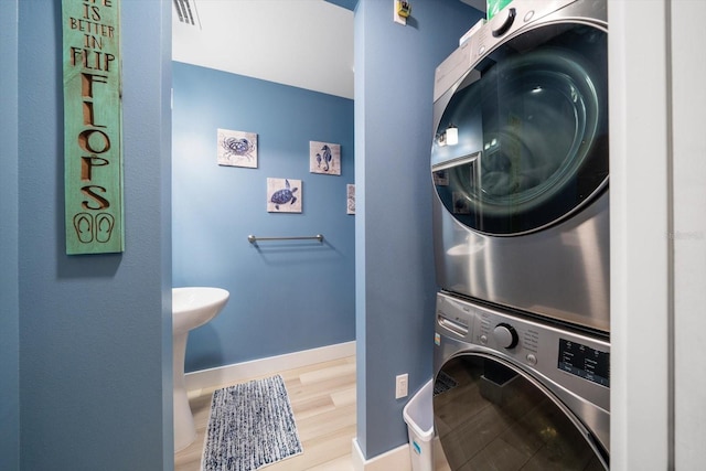 washroom with stacked washer and dryer and wood-type flooring