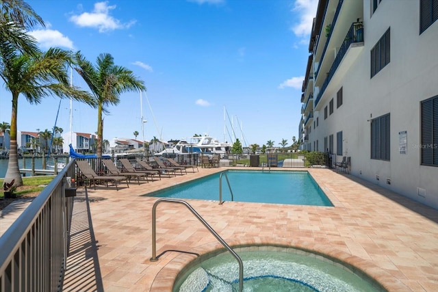 view of pool with a water view, a patio, and a hot tub