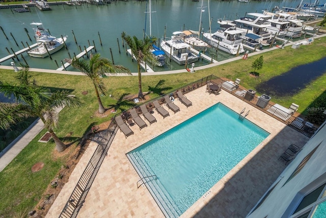 view of pool featuring a patio, a water view, a boat dock, and a yard